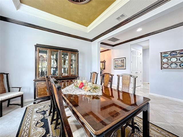 tiled dining area featuring crown molding and a raised ceiling