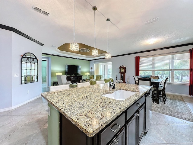 kitchen featuring a kitchen island with sink, ornamental molding, a raised ceiling, and sink