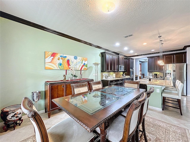 tiled dining room featuring ornamental molding and a textured ceiling