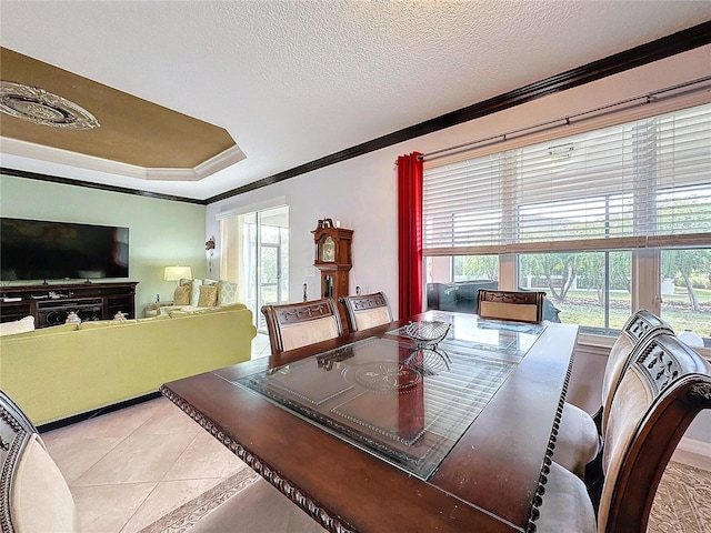 tiled dining area featuring ornamental molding, a raised ceiling, and a textured ceiling