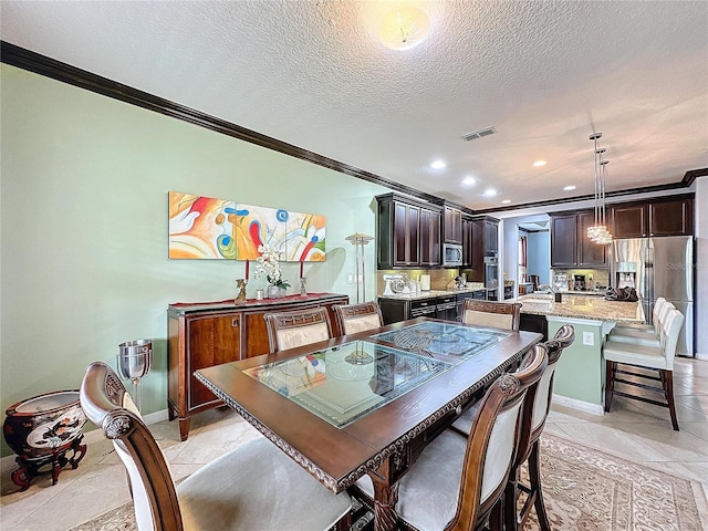 dining area with light tile patterned flooring, ornamental molding, and a textured ceiling