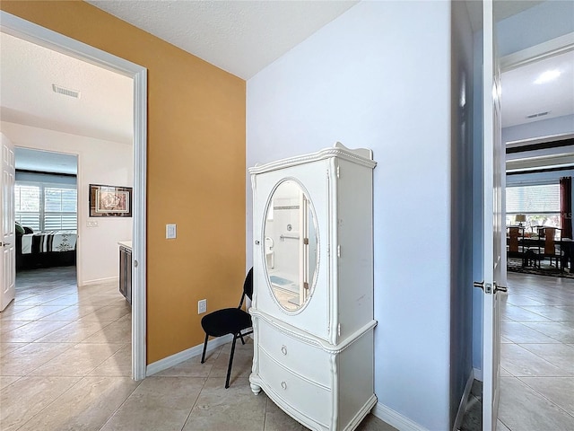 hallway with light tile patterned floors, plenty of natural light, and a textured ceiling