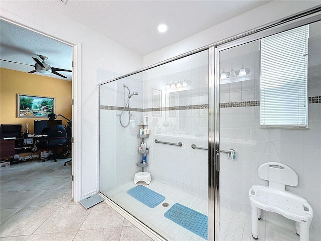 bathroom featuring ceiling fan, a shower with shower door, tile patterned floors, and a textured ceiling