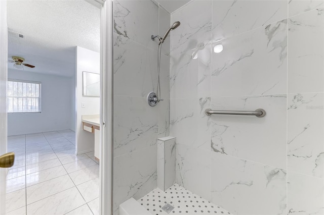 bathroom with vanity, ceiling fan, a textured ceiling, and tiled shower