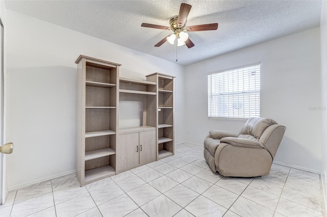 living area featuring ceiling fan and a textured ceiling