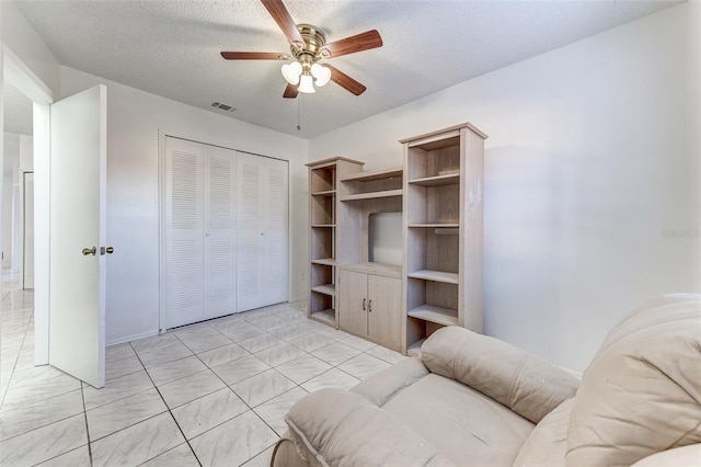 living room with ceiling fan and a textured ceiling