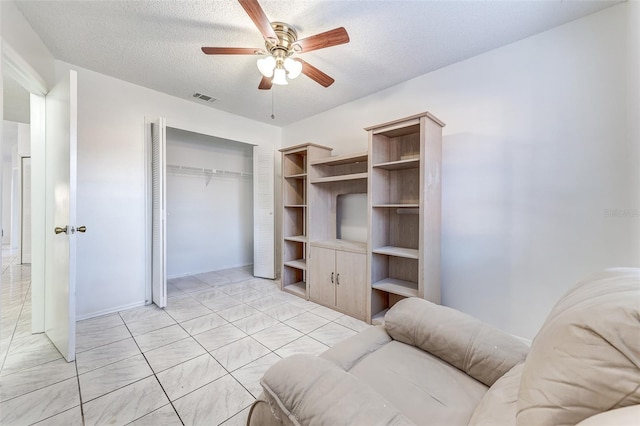 living room with ceiling fan and a textured ceiling