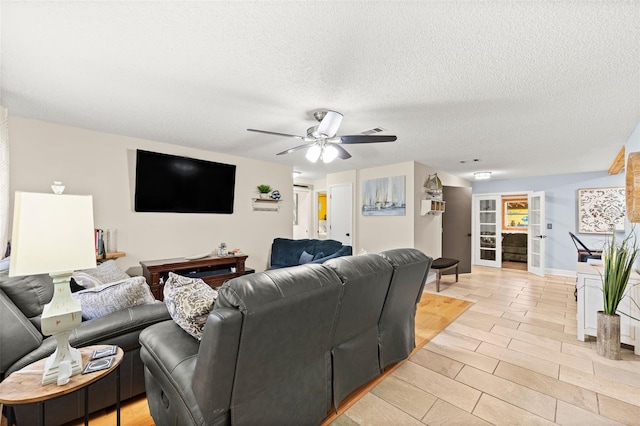 living room featuring ceiling fan, a textured ceiling, and light wood-type flooring