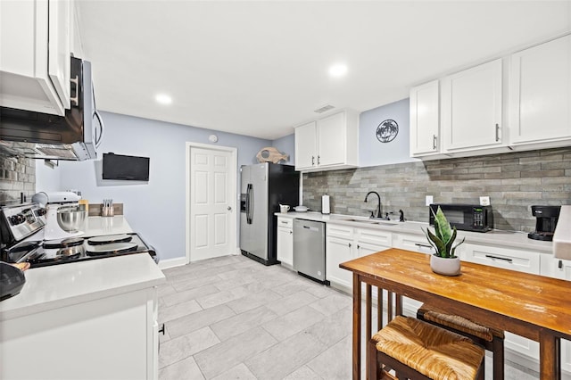 kitchen with stainless steel appliances, sink, decorative backsplash, and white cabinets