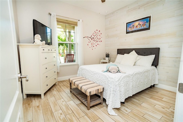 bedroom featuring light wood-type flooring and wood walls