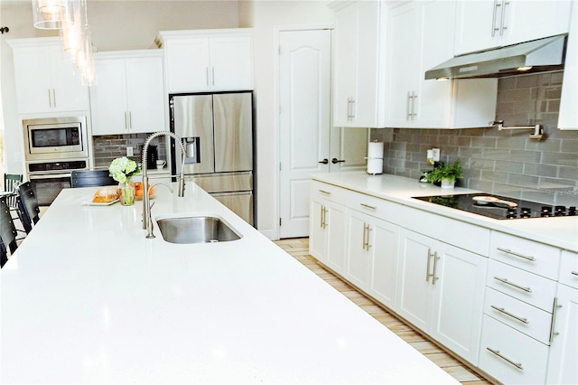 kitchen with pendant lighting, white cabinetry, stainless steel appliances, and light hardwood / wood-style flooring