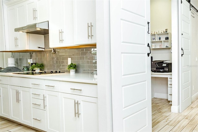 kitchen with black electric cooktop, a barn door, decorative backsplash, and white cabinets