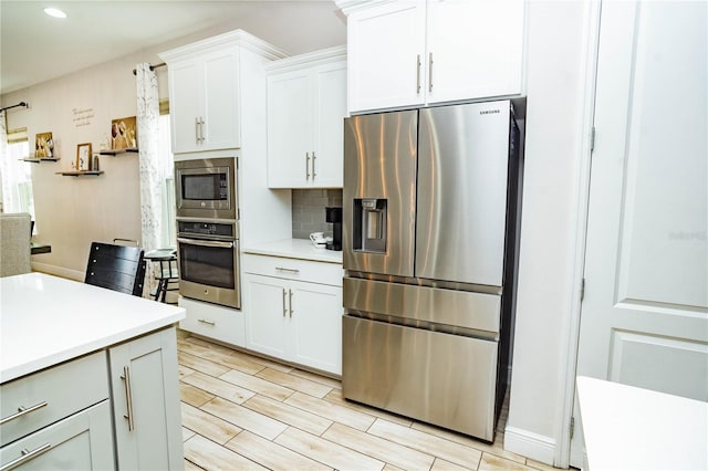 kitchen with white cabinetry, decorative backsplash, and stainless steel appliances