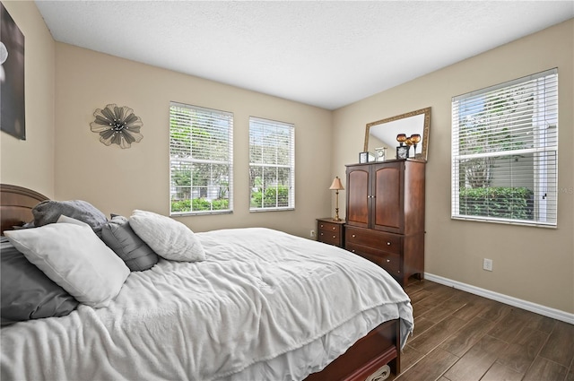 bedroom with dark hardwood / wood-style flooring, multiple windows, and a textured ceiling