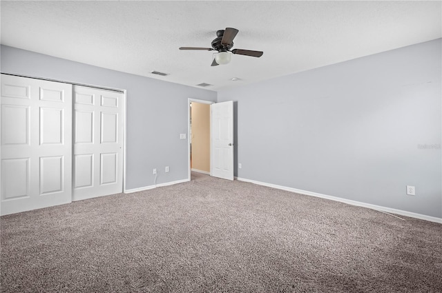 unfurnished bedroom featuring ceiling fan, carpet, a textured ceiling, and a closet