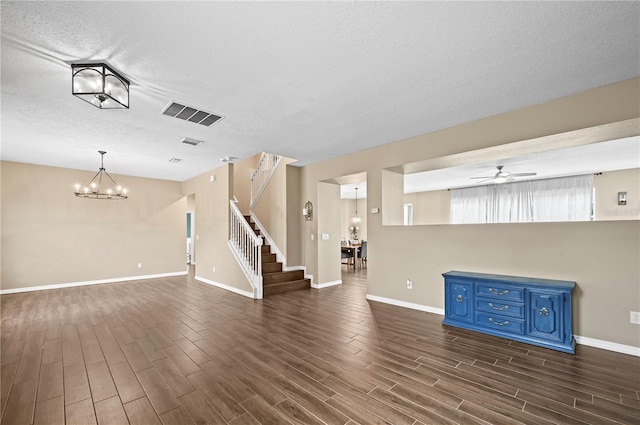 spare room with ceiling fan with notable chandelier, a textured ceiling, and dark hardwood / wood-style flooring