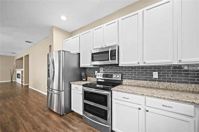 kitchen with light stone counters, appliances with stainless steel finishes, tasteful backsplash, and white cabinets