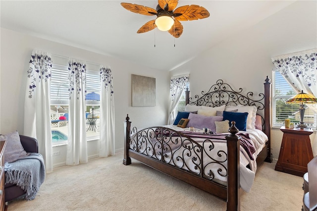 carpeted bedroom featuring ceiling fan, vaulted ceiling, and multiple windows