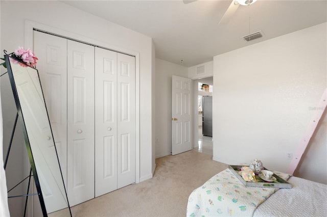 bedroom featuring ceiling fan, light colored carpet, stainless steel refrigerator, and a closet