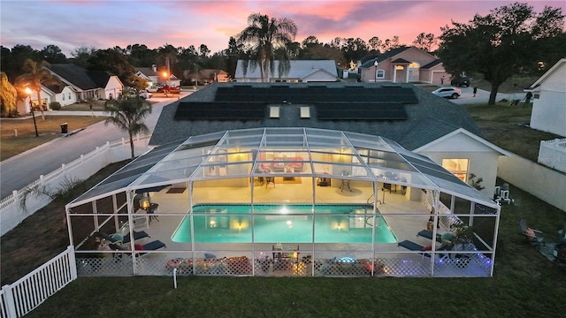 pool at dusk with a lanai, a lawn, and a patio area