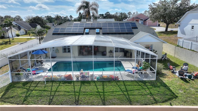 back of property with a patio area, solar panels, a lawn, glass enclosure, and a fenced in pool