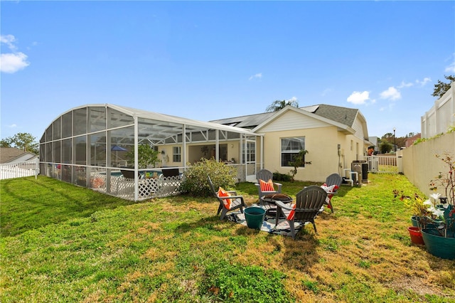 back of property with a lanai, a yard, and a fire pit