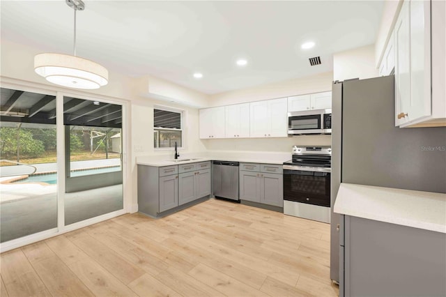 kitchen with sink, white cabinetry, appliances with stainless steel finishes, gray cabinets, and pendant lighting