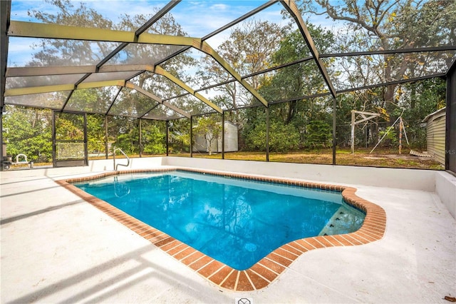 view of pool with a shed, a patio, and glass enclosure