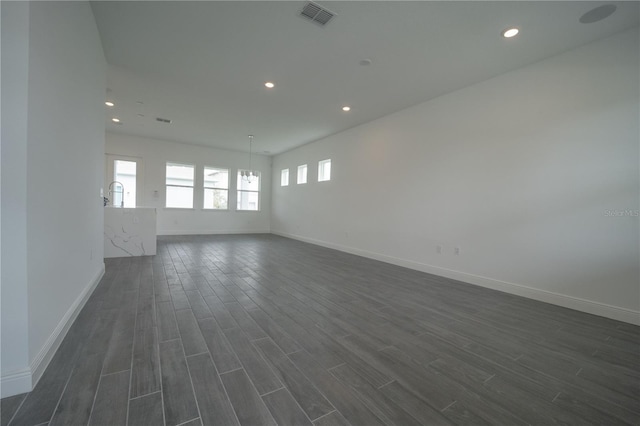 empty room featuring dark wood-style floors, visible vents, recessed lighting, and baseboards