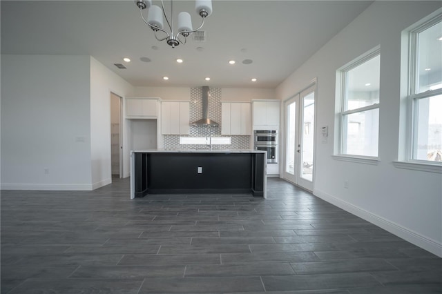 kitchen with visible vents, backsplash, an inviting chandelier, white cabinetry, and wall chimney exhaust hood