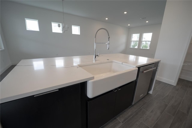 kitchen featuring a sink, dark wood finished floors, an island with sink, dark cabinetry, and stainless steel dishwasher