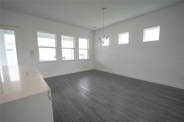 unfurnished dining area featuring baseboards, a chandelier, and dark wood-style flooring