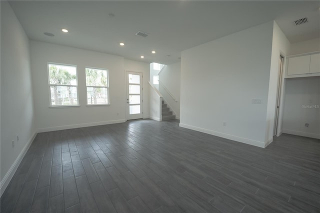 unfurnished living room featuring visible vents, baseboards, dark wood-style flooring, and stairs