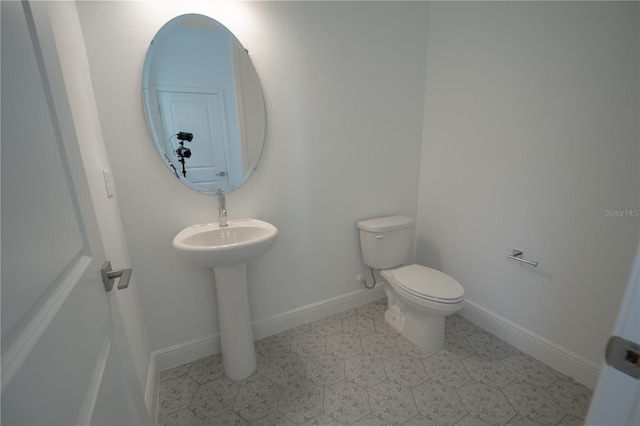 half bathroom with baseboards and toilet