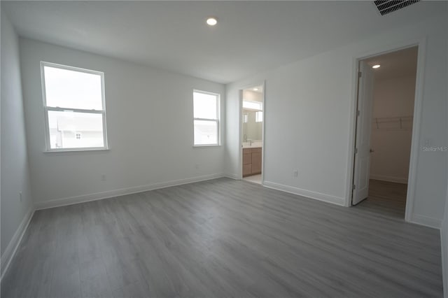 unfurnished bedroom featuring visible vents, baseboards, wood finished floors, and a spacious closet