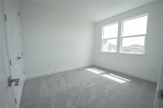 carpeted empty room featuring baseboards