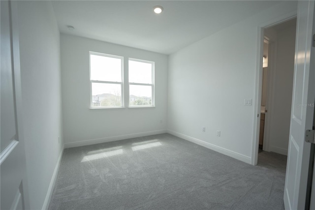 carpeted spare room featuring baseboards