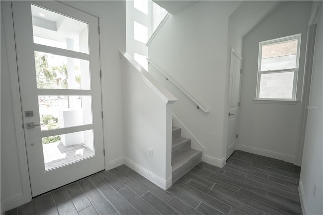 foyer entrance featuring a wealth of natural light, baseboards, stairs, and wood finish floors