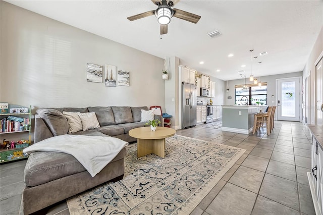 living room featuring light tile patterned flooring, sink, and ceiling fan