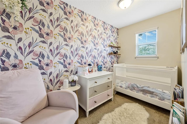 bedroom with a textured ceiling, carpet, an accent wall, and wallpapered walls