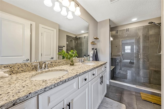 bathroom with vanity, tile patterned flooring, a shower with door, and a textured ceiling