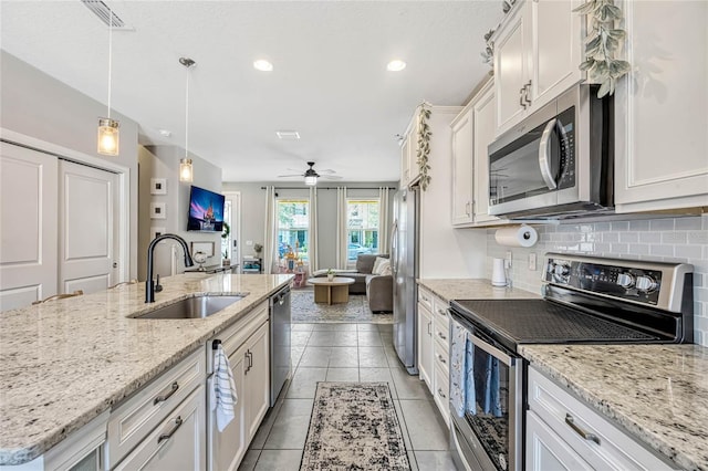 kitchen with pendant lighting, sink, appliances with stainless steel finishes, a kitchen island with sink, and white cabinets