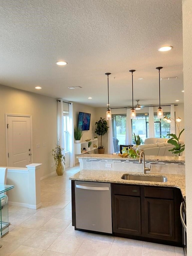 kitchen featuring stainless steel dishwasher, light stone countertops, sink, and dark brown cabinets