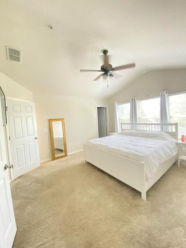 bedroom featuring ceiling fan, vaulted ceiling, light colored carpet, and a textured ceiling