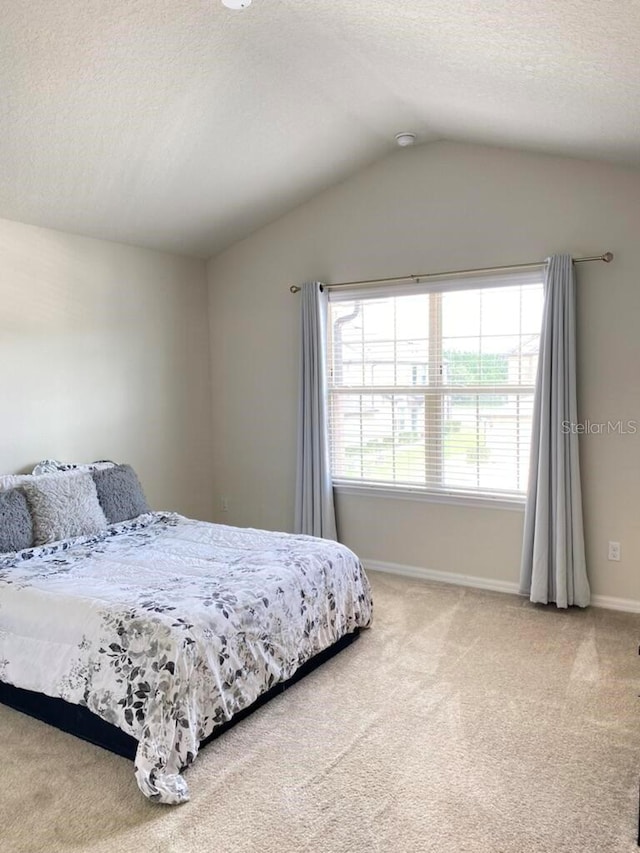 carpeted bedroom featuring vaulted ceiling and a textured ceiling