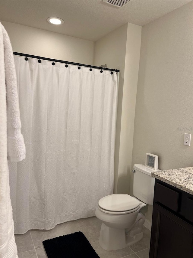 bathroom with vanity, toilet, tile patterned flooring, and a textured ceiling