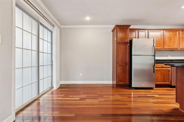 kitchen with stainless steel refrigerator, ornamental molding, and hardwood / wood-style floors