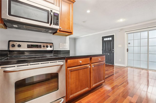 kitchen with crown molding, stainless steel appliances, and light hardwood / wood-style flooring