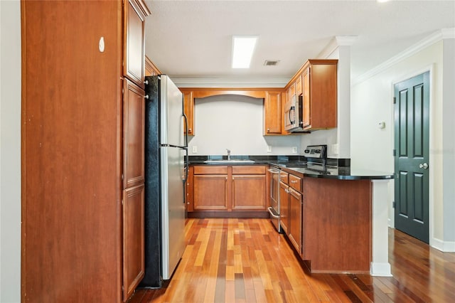 kitchen featuring sink, crown molding, stainless steel appliances, light hardwood / wood-style floors, and kitchen peninsula