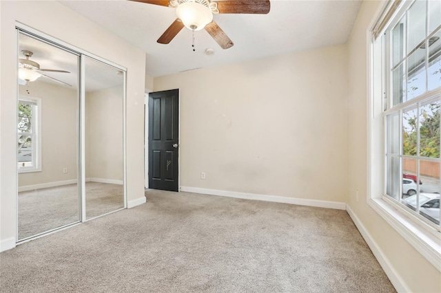 unfurnished bedroom featuring ceiling fan, a closet, and light carpet